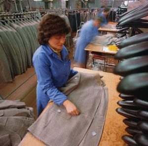A garment factory worker adds the final touches to new coats.